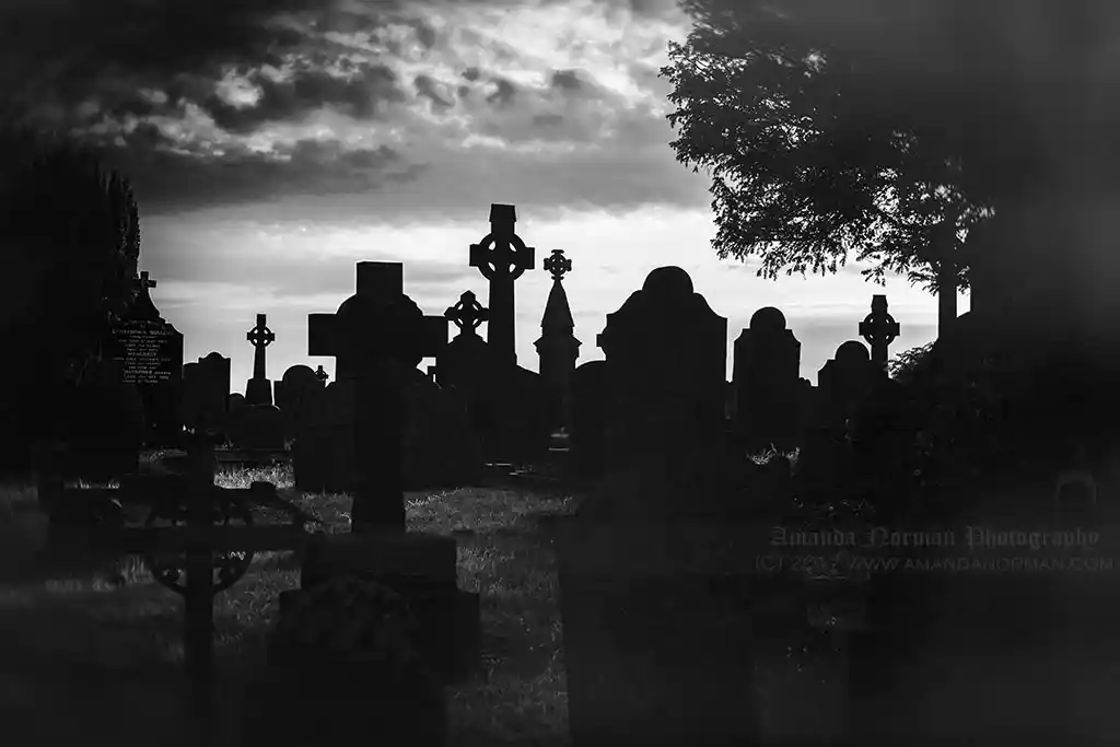 Headstones silhouetted against a sunset sky