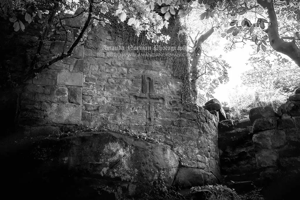 A photograph of an ancient wall with a cross on it