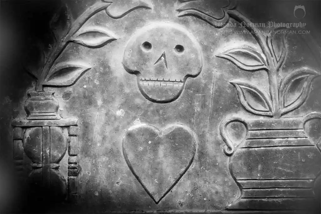 Image of a skull above a heart on a headstone
