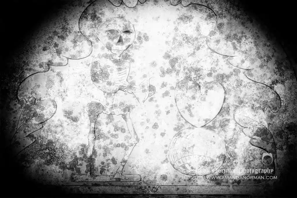 Headstone with a skeleton holding a dart