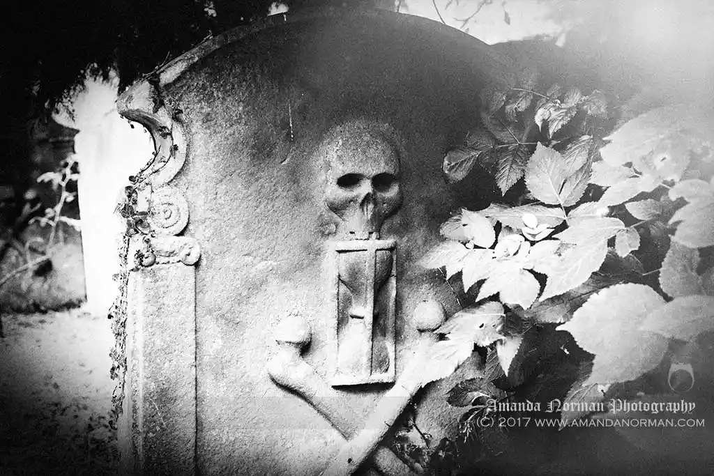 Photograph of a skull, hourglass and crossbones on a headstone in St Andrews Northumberland